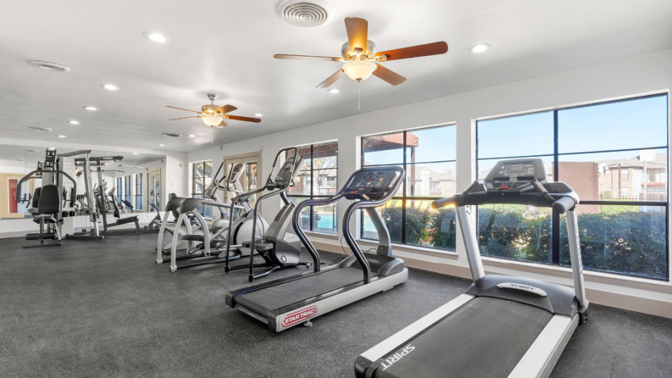 a gym room with tread machines and ceiling fans at The Brookbend