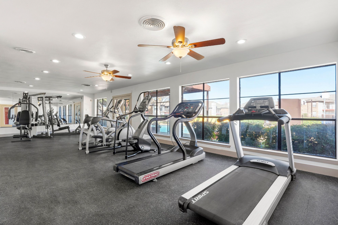 a gym room with tread machines and ceiling fans at The Brookbend