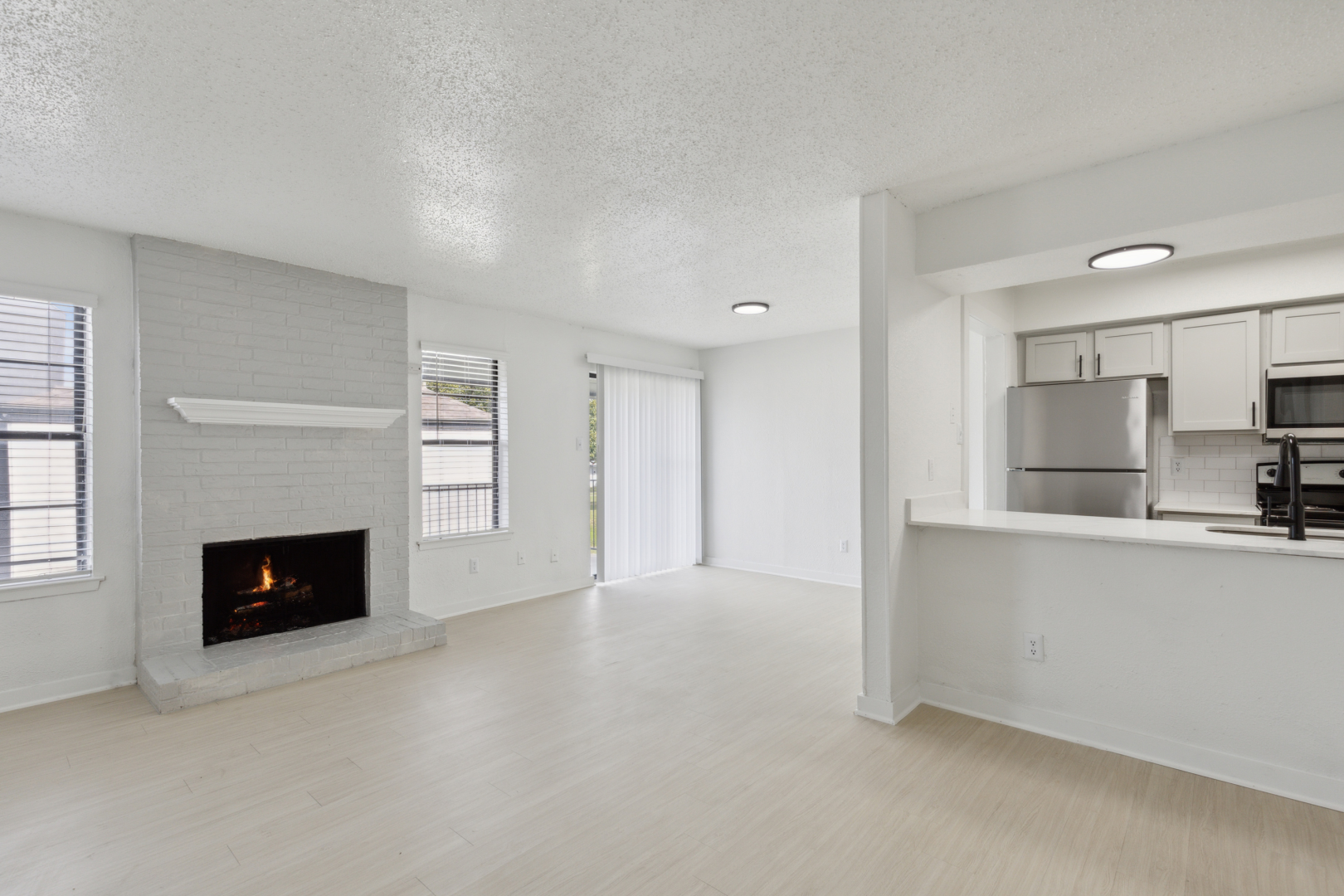 an empty living room with a fireplace and white cabinets at The Brookbend