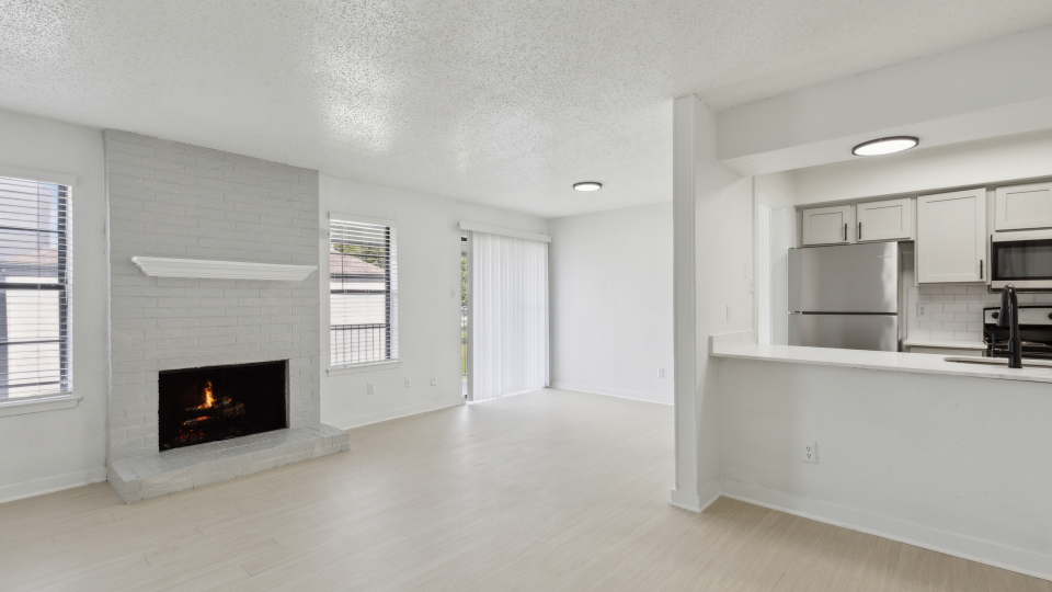 an empty living room with a fireplace and white cabinets at The Brookbend