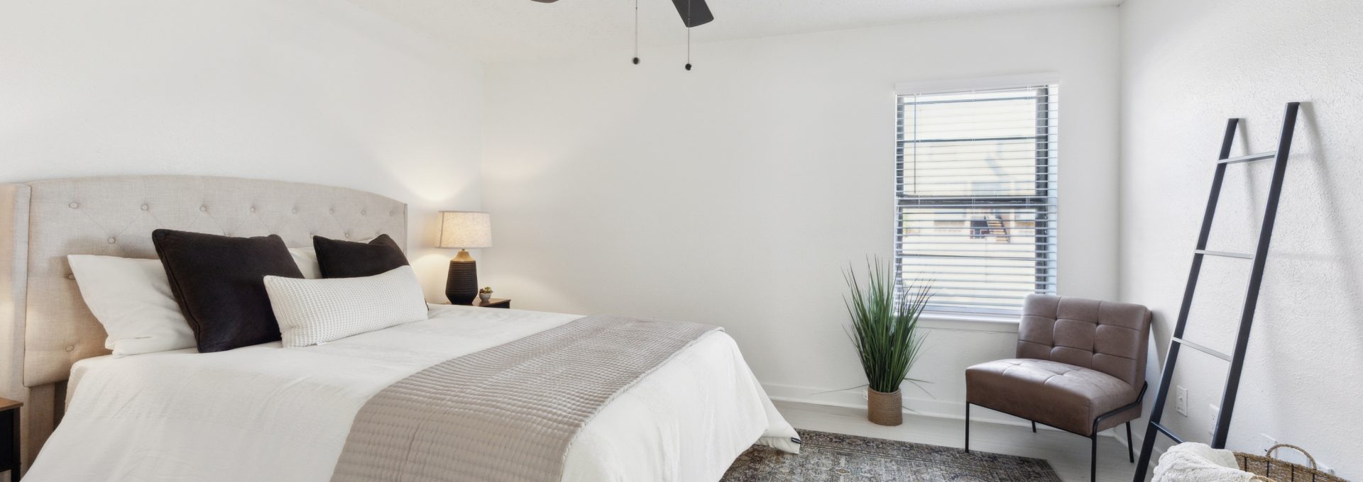 a bedroom with a ceiling fan and white bed at The Brookbend